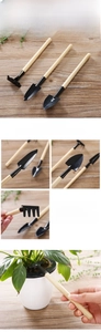 Detailed view of mini garden tool set with black metal heads and wood handles on wood table