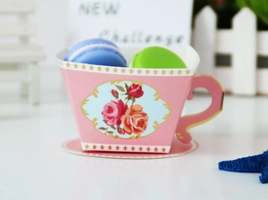 Close-up of pink cup-shaped gift box featuring floral rose patterns and macarons