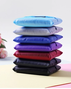 Vertical stack of folded oxford fabric shopping bags in seven diverse vibrant colors
