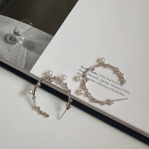 Detailed close-up of 925 silver pearl branch earrings on a minimal fashion book