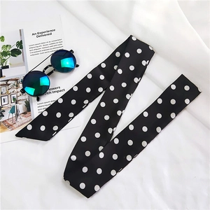 Detailed close-up of a long silk scarf with black and white polka dots pattern