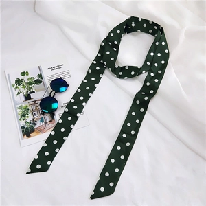 Macro detail of dark green polka dot skinny silk scarf with elegant satin finish texture