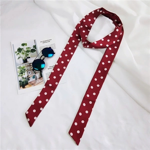 Detailed view of red silk scarf with white polka dots on a minimalist white fabric background