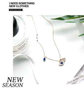 Close-up of rose gold evil eye necklace with blue stones and crystals on white silk