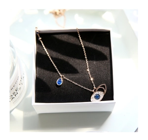 Detailed close-up of rose gold Evil Eye necklace with blue teardrop stone in gift box