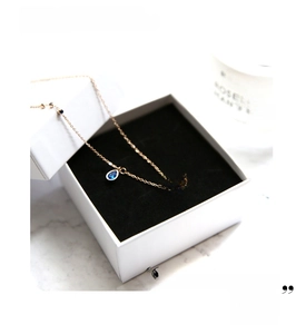 Detailed view of rose gold evil eye necklace with blue stones on black jewelry box lining
