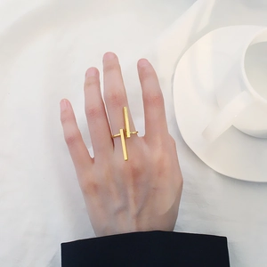 Vista dettagliata di un anello geometrico dorato minimalista indossato su sfondo bianco