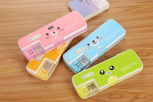 Detail of four colorful cartoon pencil cases with built-in sharpeners on a wooden desk