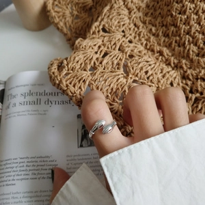Detail of S925 sterling silver hugging hands ring on fingers with artistic background