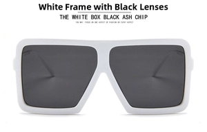 Front close-up of oversized square sunglasses with thick white frames and dark grey lenses