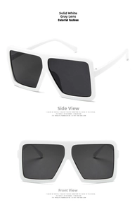 Close-up of oversized square sunglasses featuring white wide frames and dark grey lenses