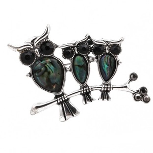Macro view of three owls brooch with iridescent abalone shell inlays and black gemstones