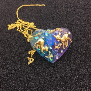 Détail du collier coeur en résine dégradé bleu-violet avec pendentifs dorés