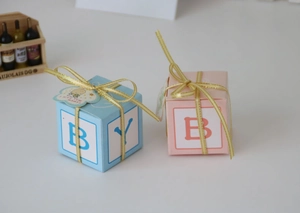 Detail of pink and blue baby shower candy boxes with gold ribbons and cute gift tags