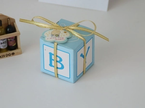 Macro shot of light blue baby shower gift box with gold ribbon and letter patterns