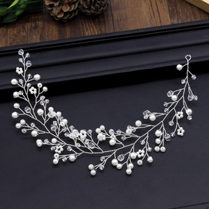 Bandeau de mariée argenté avec perles blanches et cristaux sur fond texturé noir