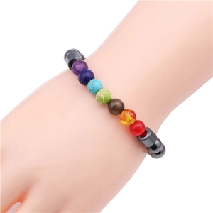 Macro shot of colorful spherical beads and black cylindrical hematite beads on a wrist