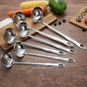 Detailed view of stainless steel spoons and slotted ladles with fresh vegetables