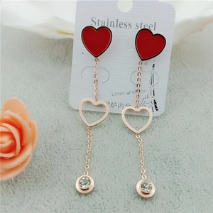 Vue macro de boucles d'oreilles longues à pampilles cœur rose doré et pierres zircons