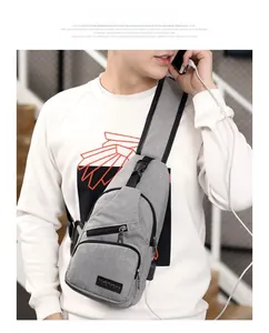 Detailed view of gray sling bag featuring integrated USB charging port and zipper pockets