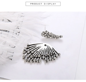 Detailed view of silver crystal wing earrings set on a white feather backdrop