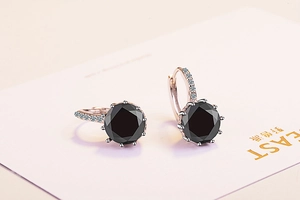 Macro view of rose gold earrings with round black zircon stones and micro-pave crystals