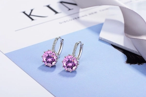 Detailed close-up of silver earrings featuring large round pink zircon and white diamonds