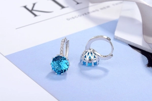 Macro detail of S925 sterling silver hoop earrings with blue round-cut zircon crown setting