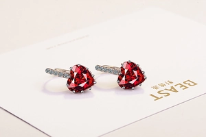 Detailed close-up of heart-shaped ruby earrings with silver pavé cubic zirconia