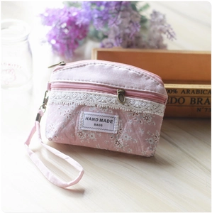 Detailed close-up of pink floral fabric coin purse with white lace trim and handmade tag