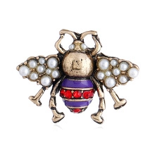 Macro detail of vintage gold bee earring with white pearls and red rhinestones