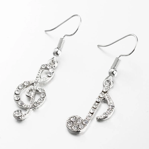Detail van asymmetrische muzieknoot oorbellen in zilver met fonkelende strassteentjes