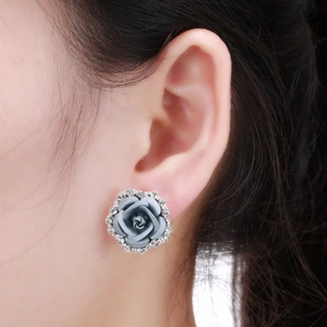 Close-up of elegant grey rose stud earring with sparkling white rhinestones on ear