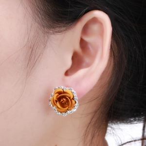 Detailed view of an orange rose earring with white rhinestones on a female model
