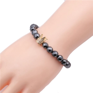 Macro detail of 8mm faceted magnetic hematite beads with a gold zircon crown charm