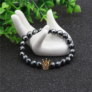 Detail of 8mm faceted magnetic hematite beads with a gold micro-pave crown on a hand model