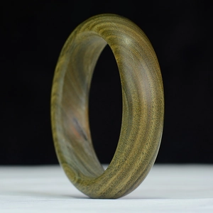 Primer plano de un brazalete de sándalo pulido con vetas naturales y textura de seda