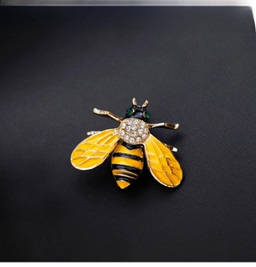 Detailed macro of golden bee brooch with yellow enamel wings and sparkling rhinestones