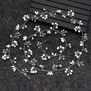 Detailed view of silver bridal hair vine with white pearls and crystals on dark felt background