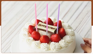 Close-up of slender pink and purple candles on a strawberry cream birthday cake decoration