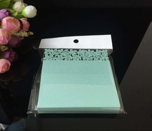 Detailed laser-cut mint green wedding table cards with floral patterns in packaging