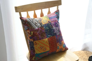 Detail of bohemian cotton linen cushion with colorful patchwork on a wooden chair
