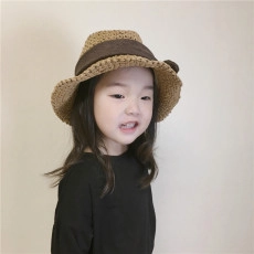 Detailed view of child's khaki straw hat featuring a dark brown ribbon bow decoration