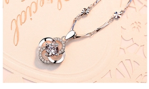 Detailed view of silver rotating clover pendant necklace with sparkling inlaid crystals