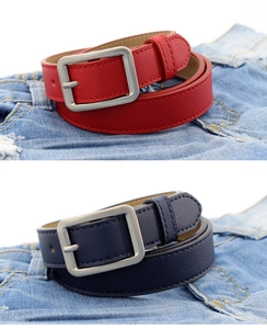 Close-up of red and navy leather belts with matte silver square buckles on denim fabric