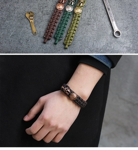 Detail of woven paracord bracelets in brown and green with Spartan helmet metal charms