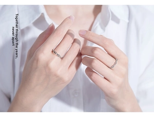 Close-up of silver-colored couple rings with infinity design and zircon inlays on hand