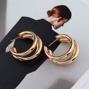 Close-up of golden triple-layered hoop earrings with high-polish mirror finish