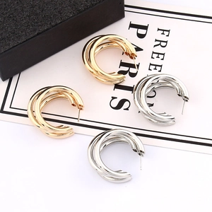 Close-up of triple layered gold and silver irregular geometric hoop earrings on white background