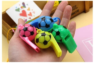 Hand holding four colorful plastic soccer whistles in blue, pink, yellow, and green